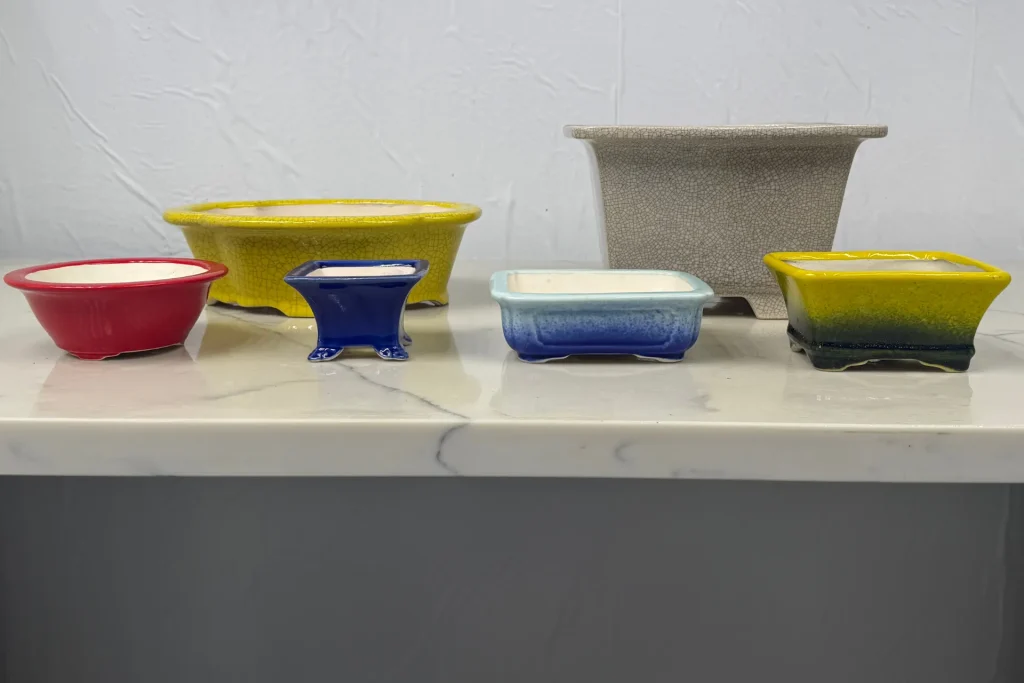Display of glazed pots in various colours, shapes and sizes on marble indoors