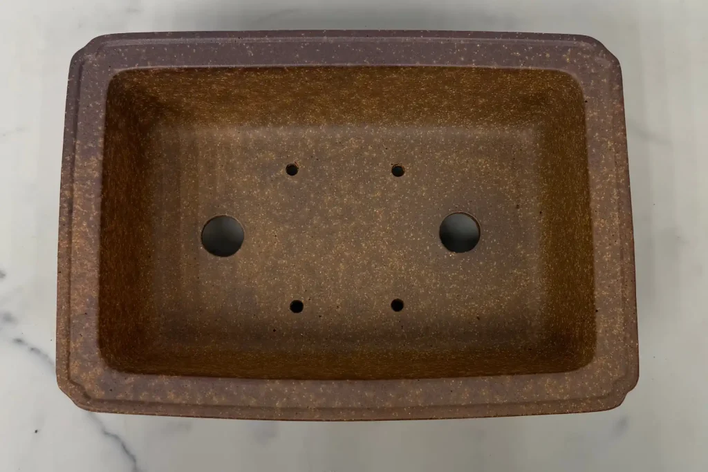 Above shot of empty bonsai pot with drainage and wiring holes clearly visible
