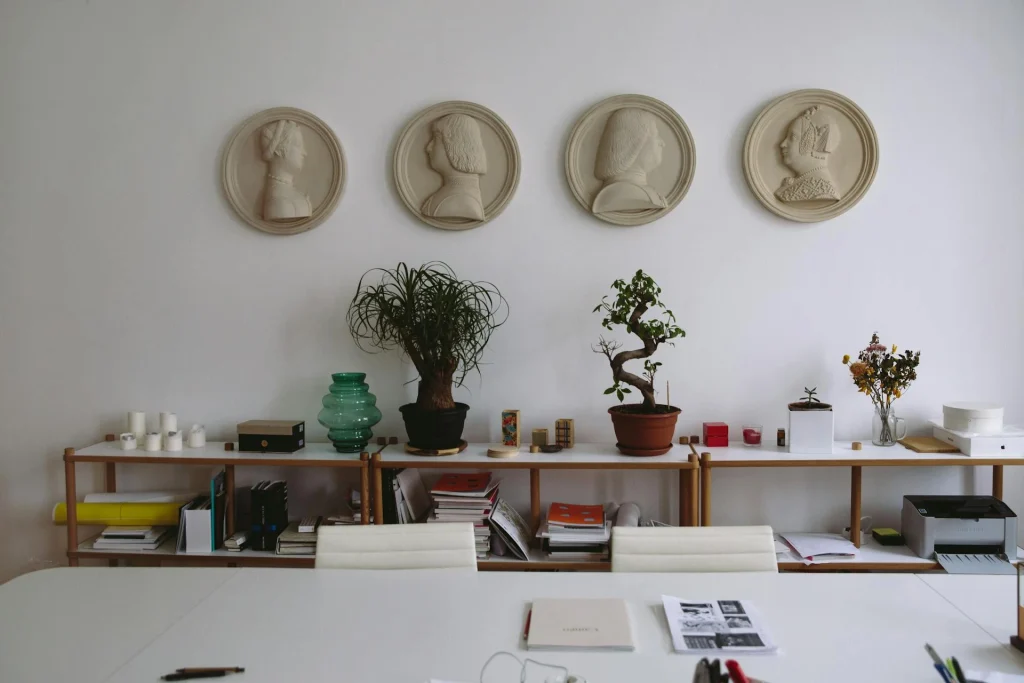 Indoor office with ceramic busts on the wall and shelves, a couple of bonsai along the shelves