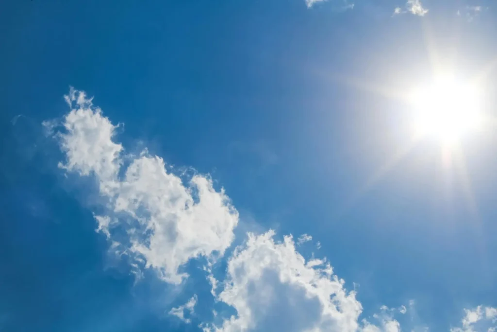 Summer sky with clouds spreading across the bottom and a clear sun in the top right corner